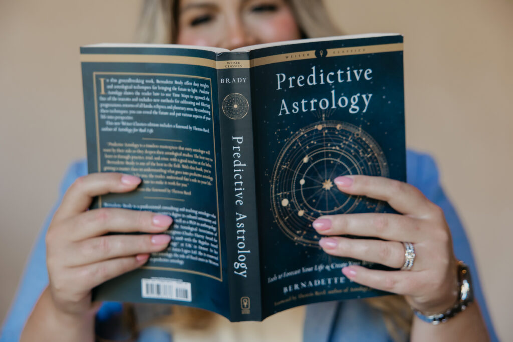 Caitlin Weseman reading Predictive Astrology, her hands framing the star chart cover