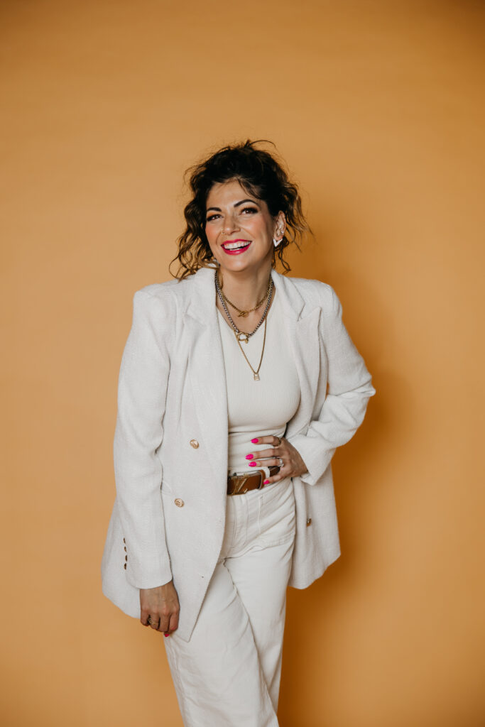 Woman in a white blazer with a brown belt, a bold headshot outfit idea on mustard