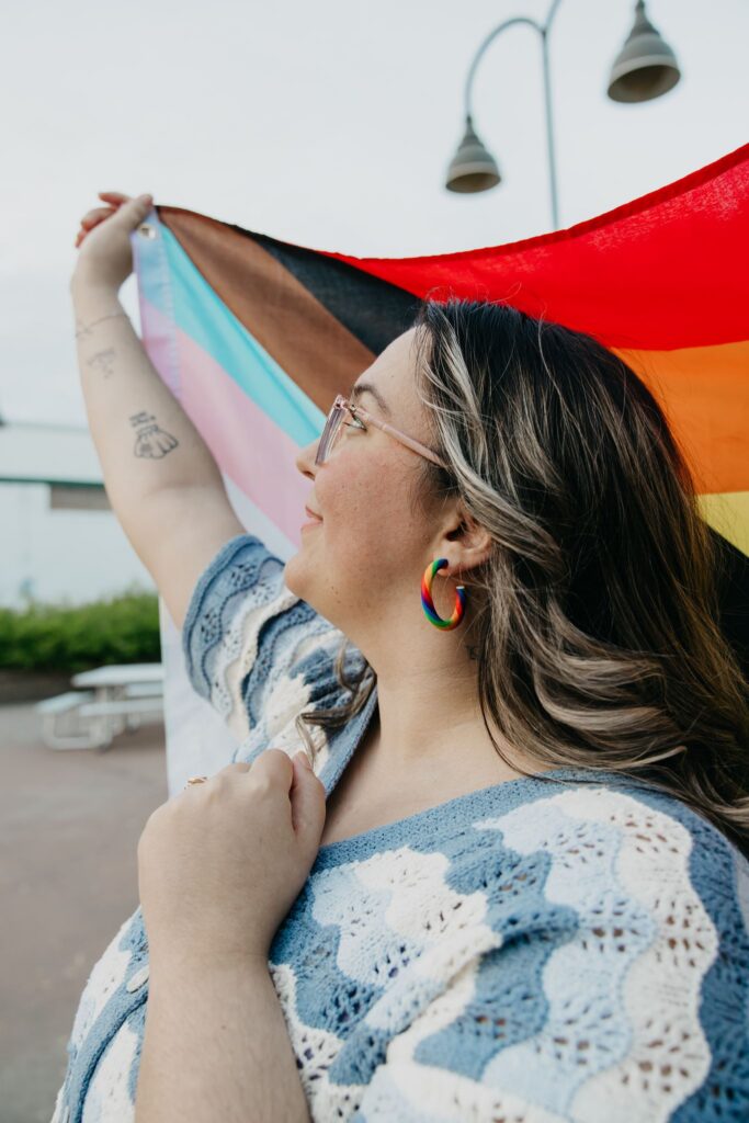 Woman holding a Progress Pride flag overhead during a Minneapolis group brand photography session