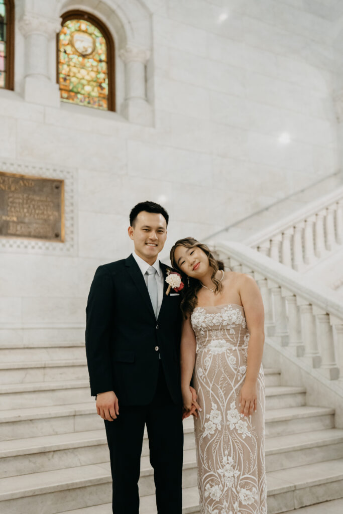 Bride and groom standing together on a marble staircase inside the courthouse