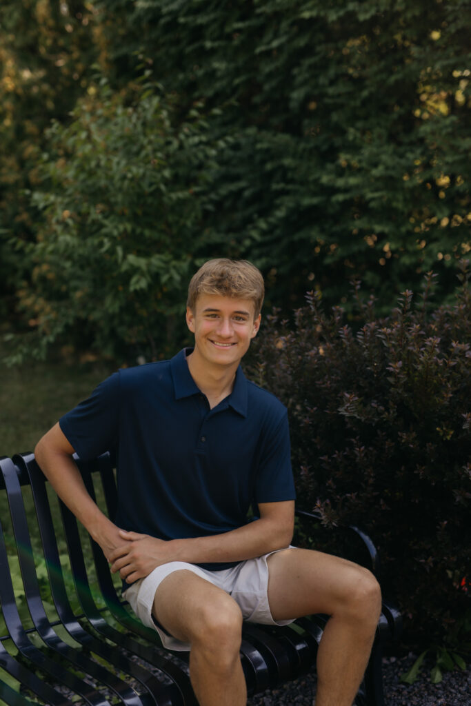 Senior guy sitting on a park bench in a navy polo shirt