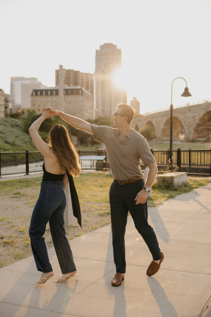 Engaged couple sharing a twirl dance outdoors in Minneapolis at sunset