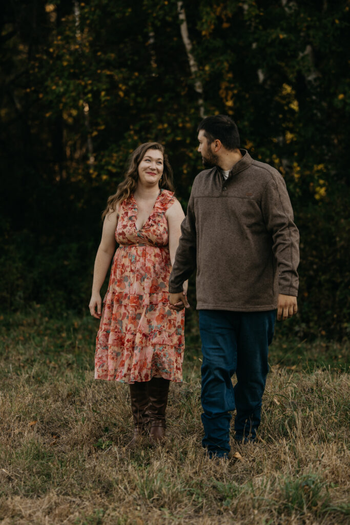 Couple standing face to face laughing in a sunlit golden field