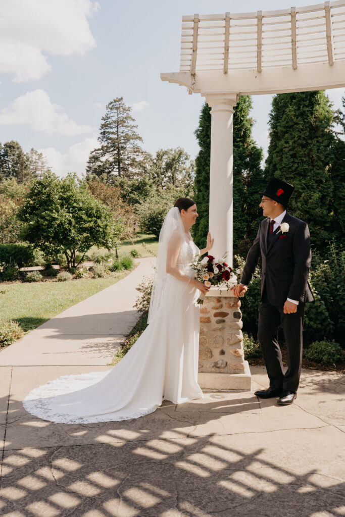 Bride and groom stand near the white pergola on the grounds at Keller Golf Course