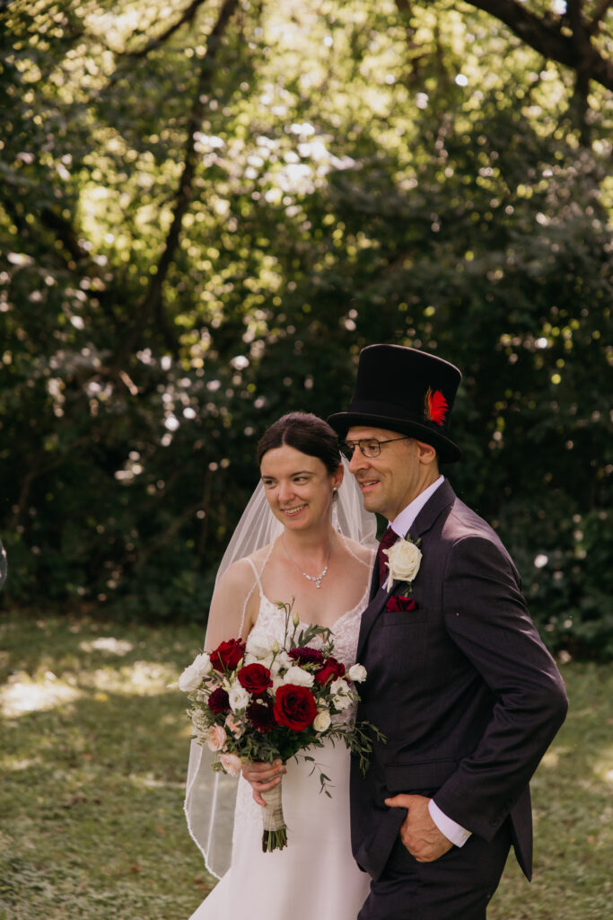 Close portrait of bride and groom smiling together, groom in a black top hat