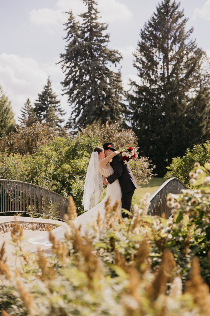 Groom carries bride across a stone footbridge at their Keller Golf Course wedding in Maplewood
