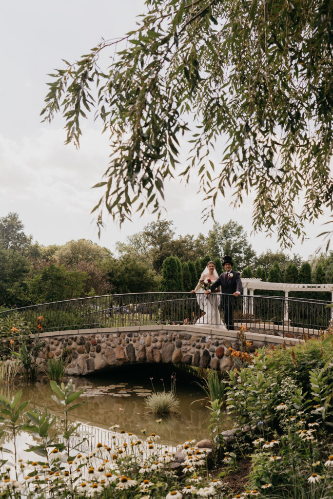 Bride and groom stand together on the stone footbridge at Keller Golf Course, pond below