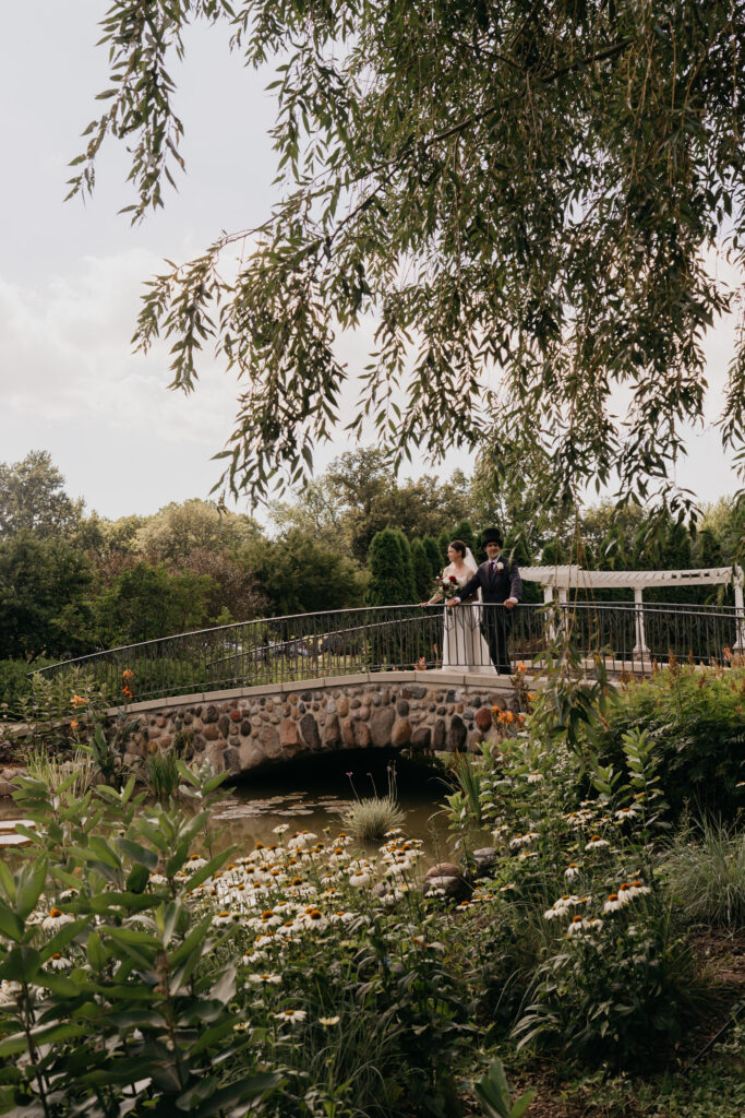 Wide shot of bride and groom on the Keller Golf Course footbridge framed by willow branches