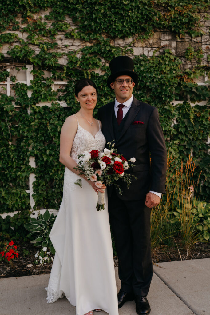 Bride and groom pose in front of the ivy wall at their Keller Golf Course wedding
