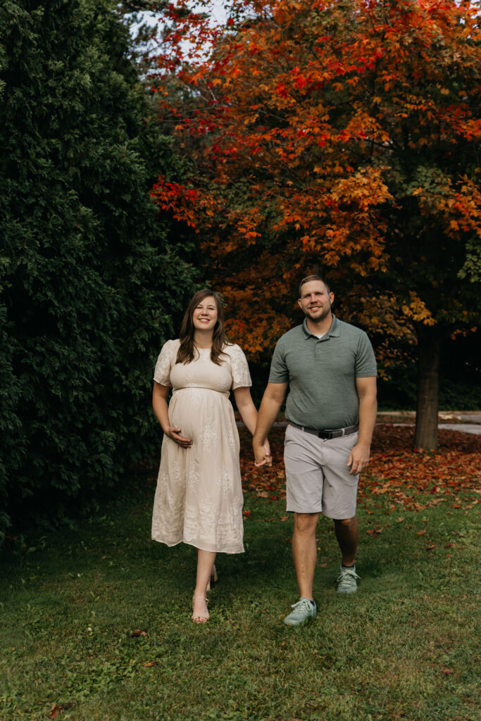 Couple holding hands and walking past vibrant fall foliage
