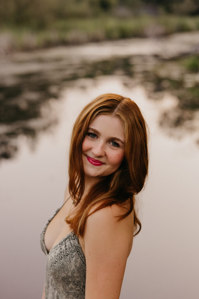 Minneapolis senior smiling over her shoulder in a sage green patterned dress