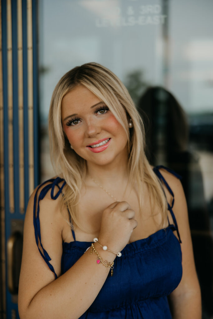 Senior girl in a navy top smiling in a glass-paneled doorway