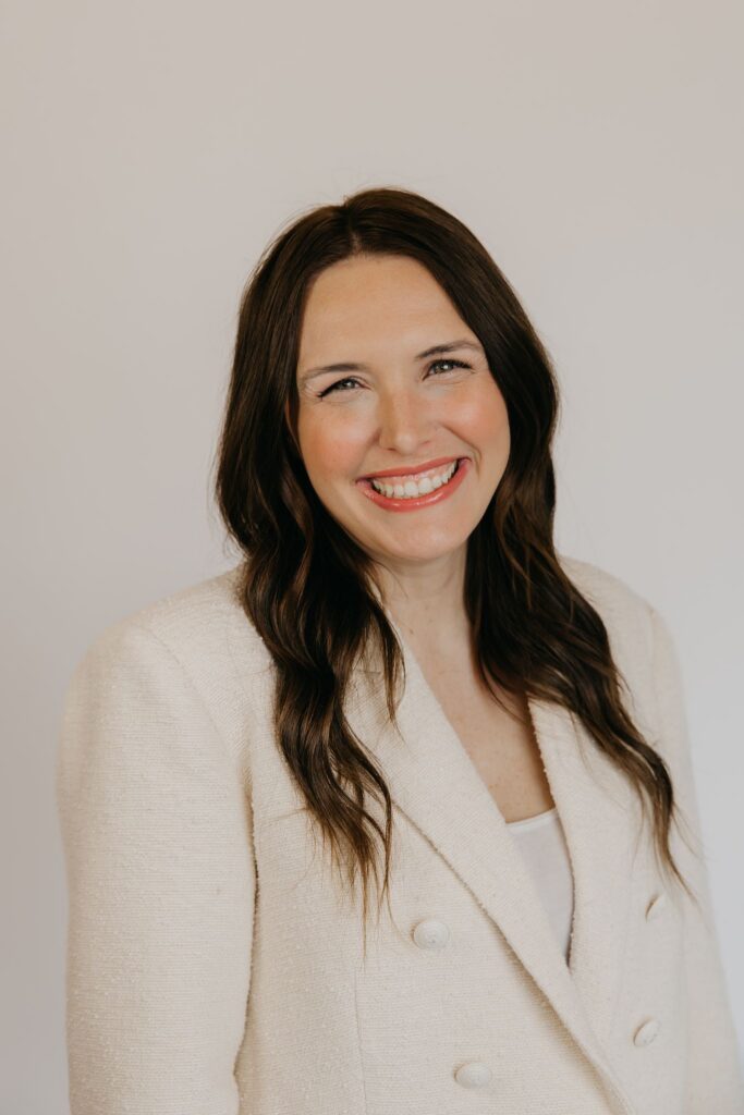 Woman in a cream bouclé blazer smiling in a close-up headshot on a neutral backdrop