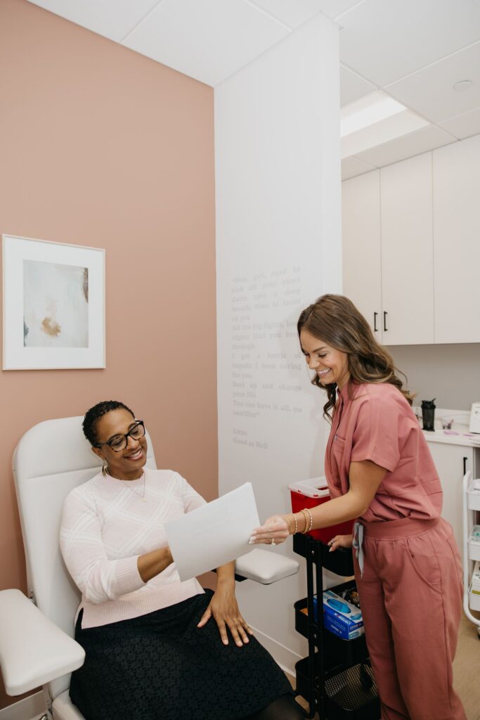 Integrative medicine provider in pink scrubs reviewing paperwork with a patient in an exam room