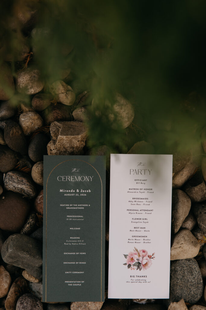 Ceremony and reception programs rest on a bed of rocks in the venue's landscaping