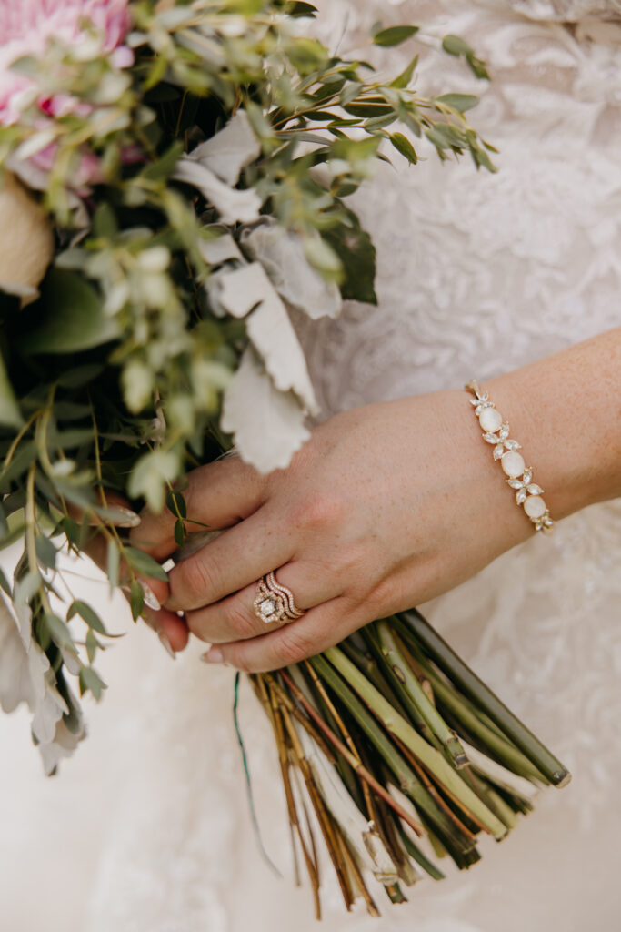 Bride's hand holding her bouquet, rings visible on her fingers