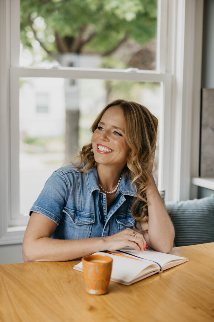 Creative business owner smiling with her hand resting on her cheek at a wooden table