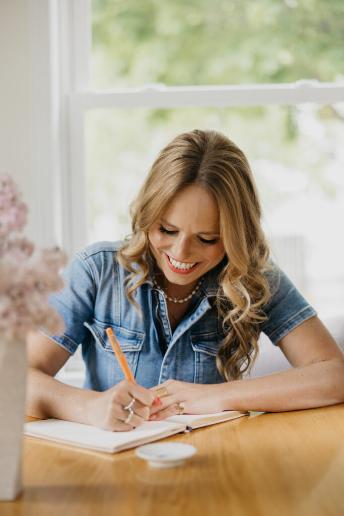 Creative business owner writing in a journal at a sunlit table