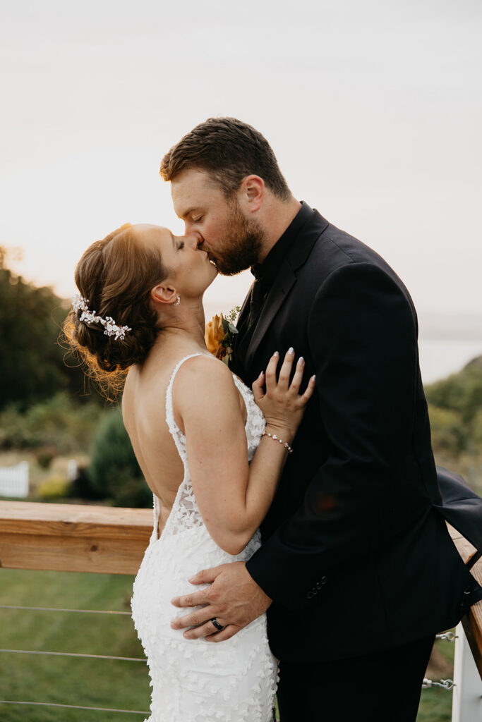 Bride and groom sharing a kiss on an outdoor deck railing