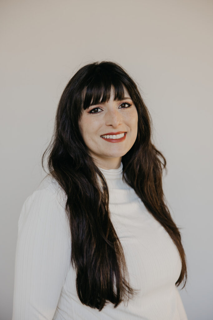 Woman with dark bangs in a white turtleneck, a clean example of what to wear for headshots