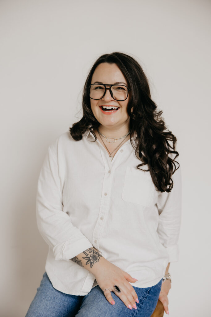 Woman in glasses and a white shirt laughing, showing what to wear for headshots