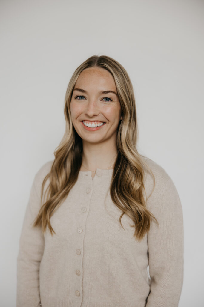Blonde woman in a cream cardigan smiling in a soft, neutral professional headshot
