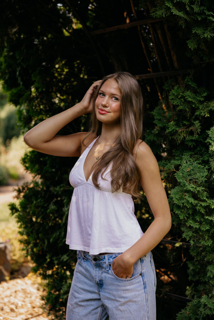 Senior with hand in her hair smiling on a brick garden path