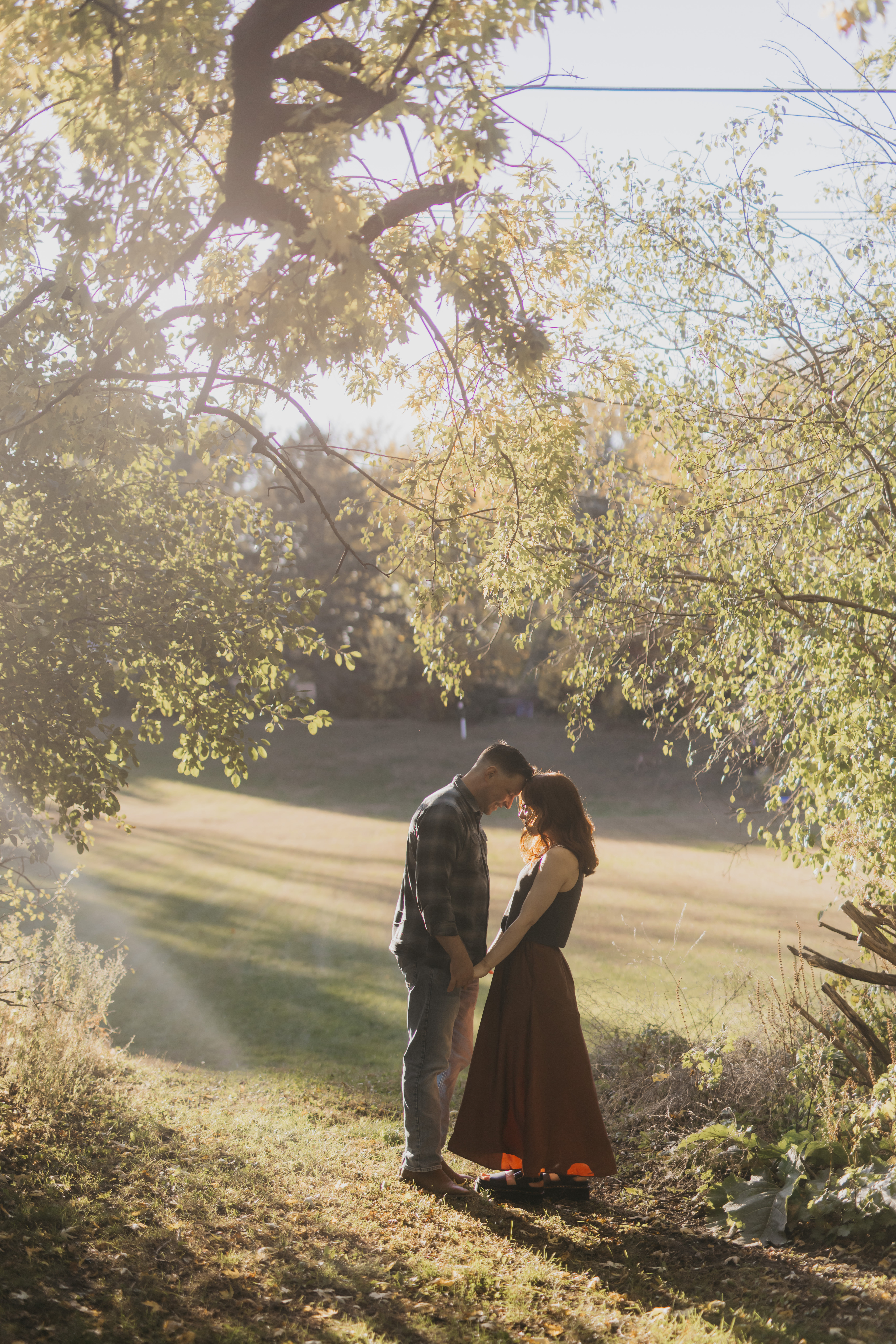 Engaged couple standing forehead to forehead under golden fall trees during a Minneapolis engagement session