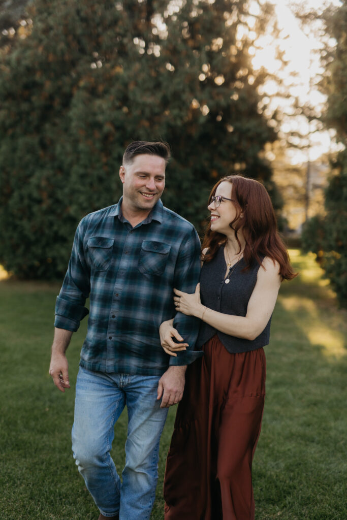Engaged couple walking together and laughing outdoors during a fall engagement session
