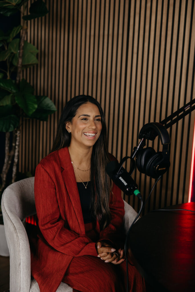 Personal branding photography for entrepreneurs: Tatiana Budney in a red duster suit holding a podcast microphone