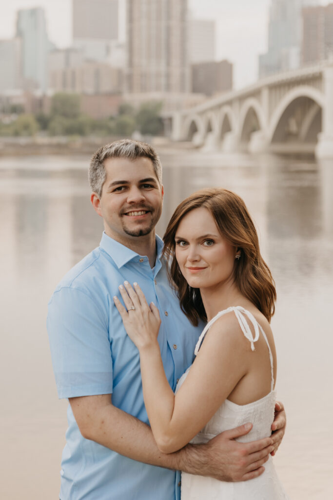 Close portrait of a smiling couple in front of the river and downtown Minneapolis bridge