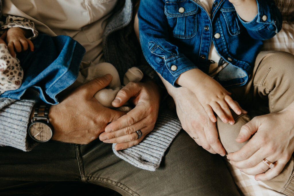 Family members' hands and feet gathered together in denim outfits during a newborn session