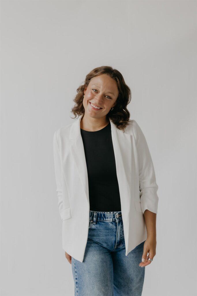 Woman in a white blazer over a black top and jeans, a casual headshot outfit idea
