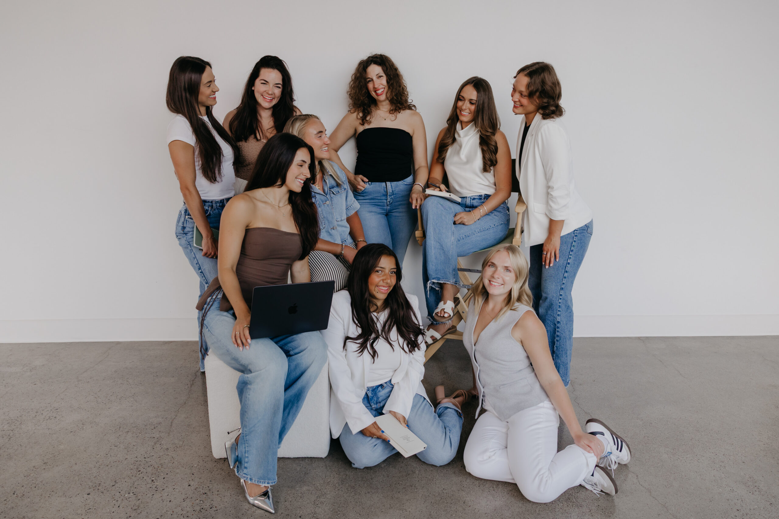 Nine women from The Wellthy Circle posed together in denim and neutrals for group brand photography in a Minneapolis studio