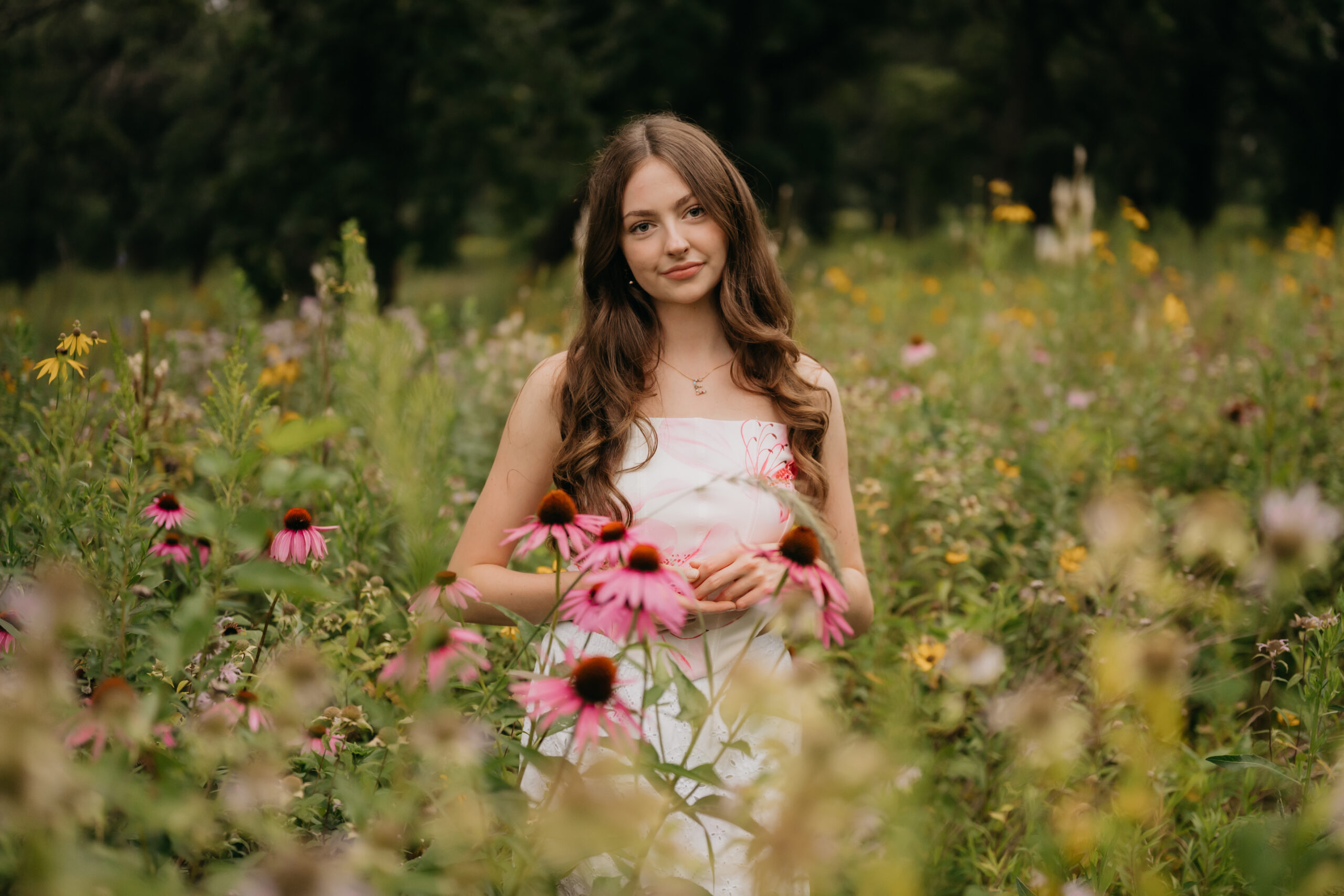 Minneapolis high school senior in a white floral dress standing among pink coneflowers in a wildflower field