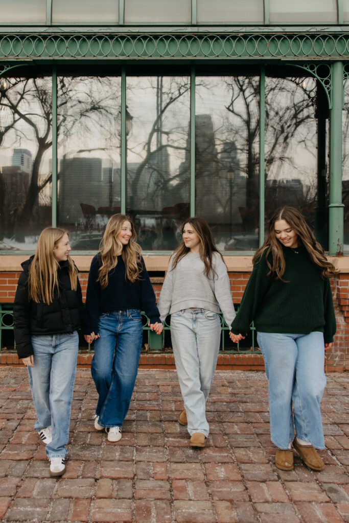 High school senior friends laughing as they walk across brick pavement in downtown Minneapolis