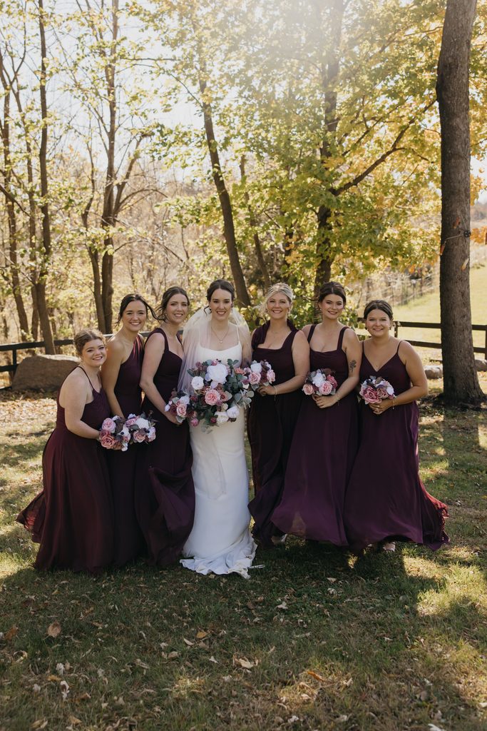 Bride with her bridesmaids in burgundy dresses holding pink and white bouquets