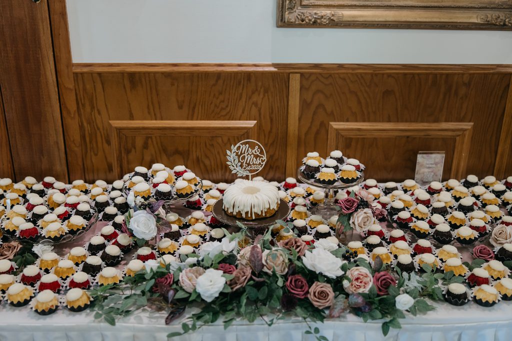 Nothing Bundt Cakes wedding dessert table with a Mr and Mrs topper and blush roses