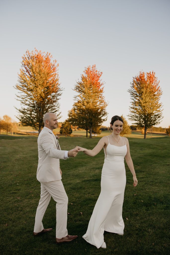 Ridges at Sand Creek wedding portrait of groom leading bride by the hand at golden hour