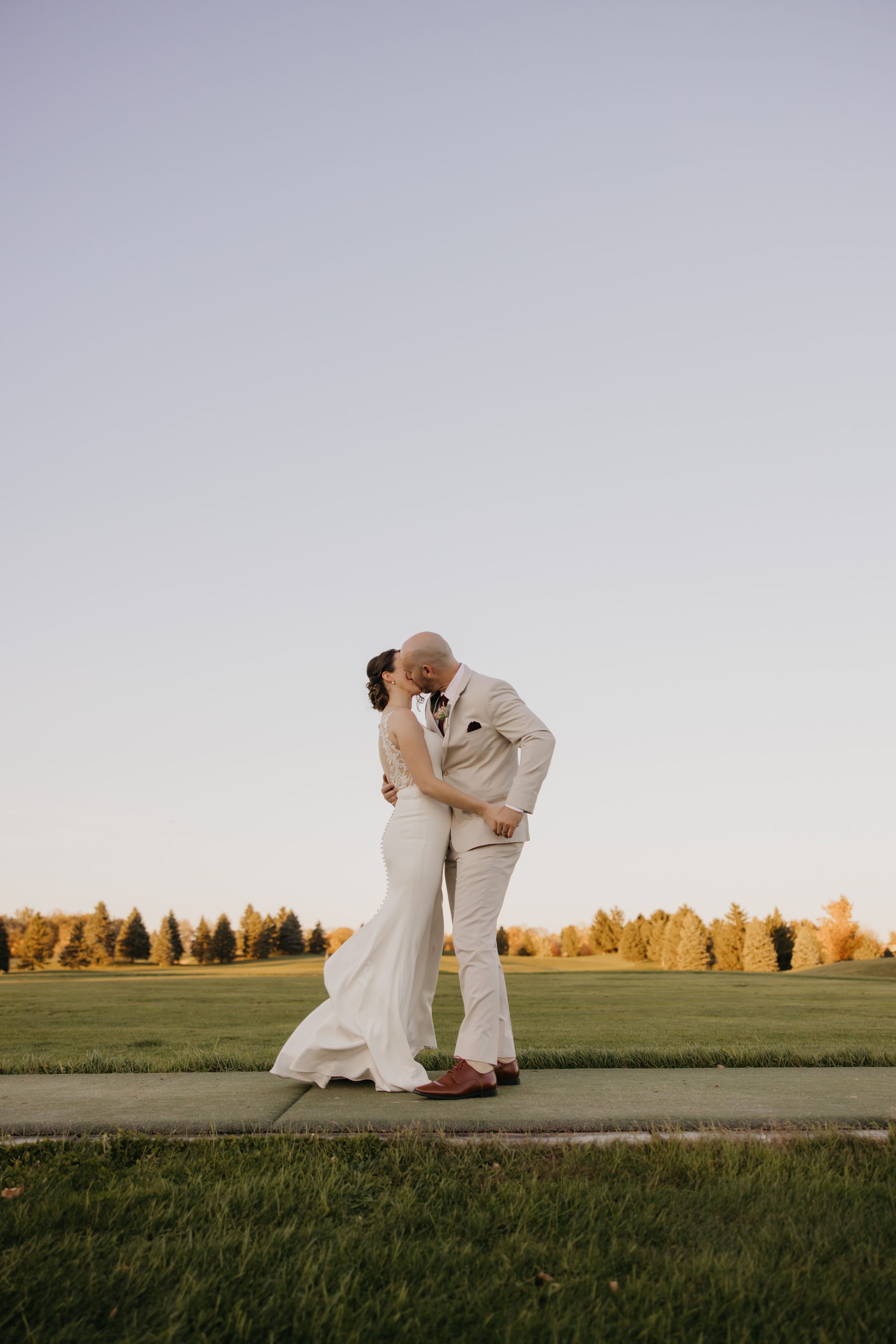 Bride and groom kiss on a golf course path at Ridges at Sand Creek