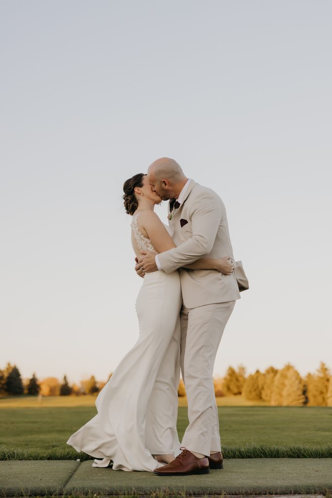 Bride and groom kiss on a golf course path at Ridges at Sand Creek