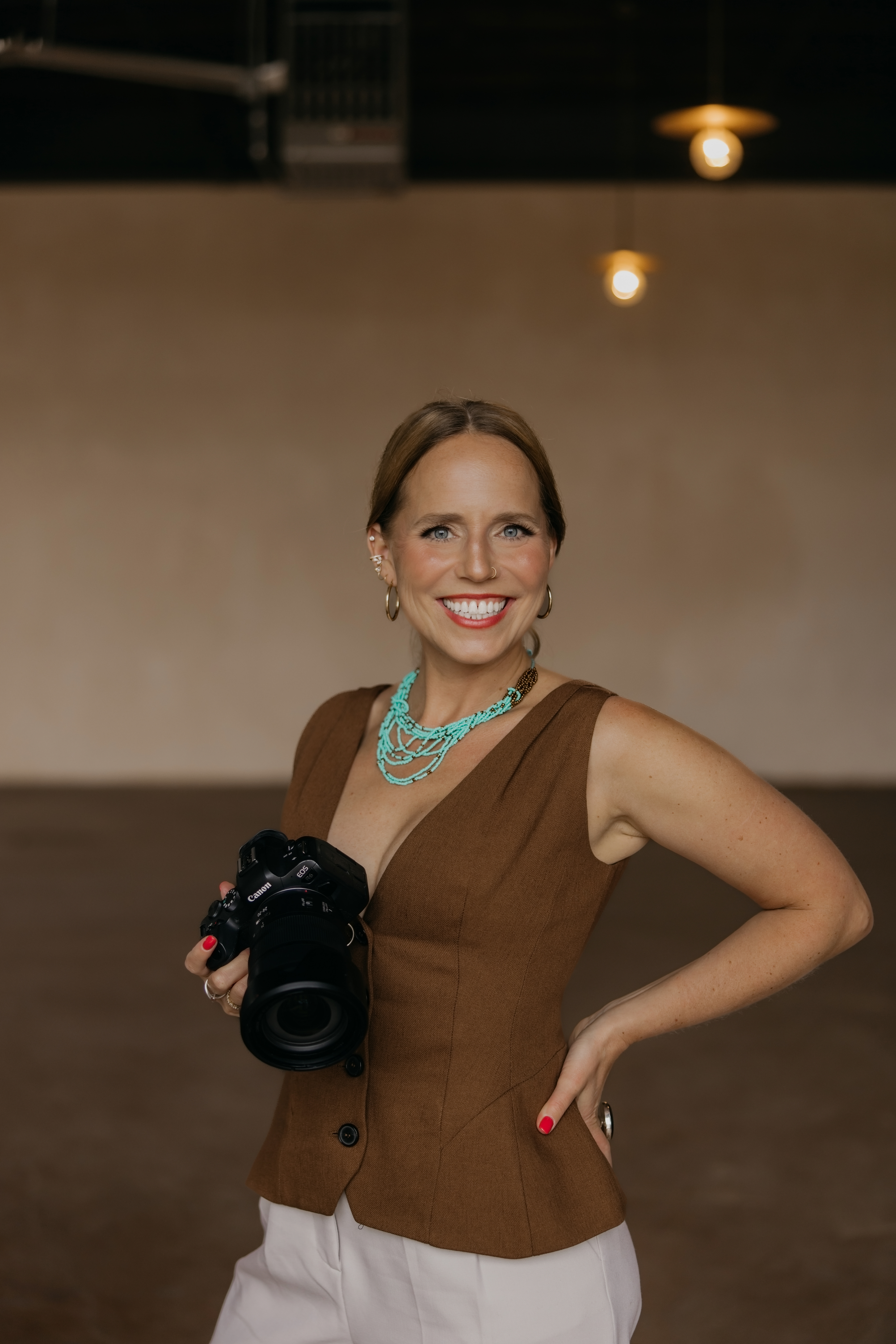 Mycah Bain smiling with her Canon camera in a warm Minneapolis studio, photographer for professional headshots