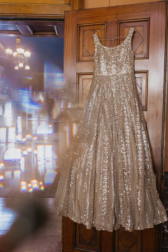 Sparkling champagne-colored wedding gown hangs on a wooden door