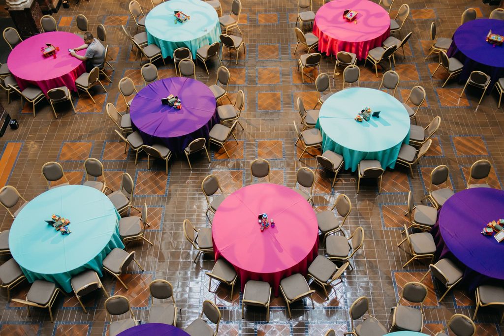 Overhead view of round reception tables with pink, teal, and purple linens in an Indian wedding reception
