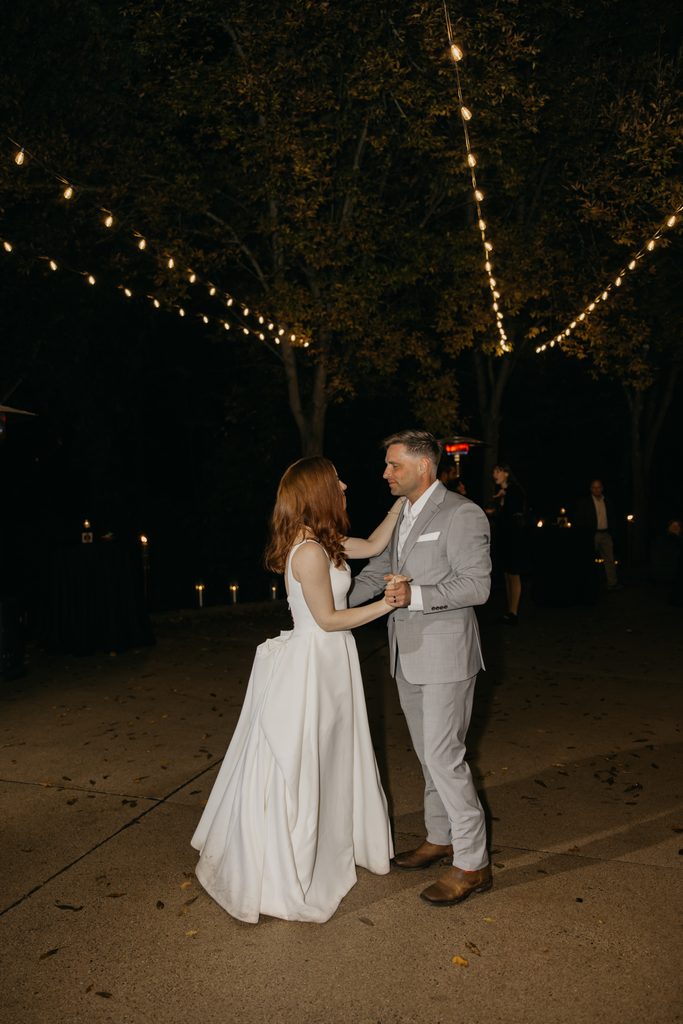 Stephanie and Seth slow dancing under string lights at night