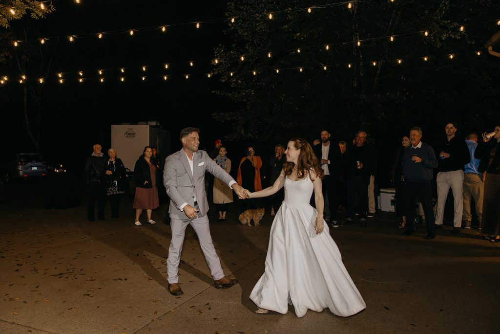 Stephanie and Seth begin their dance under string lights as guests watch at their St. Cloud reception