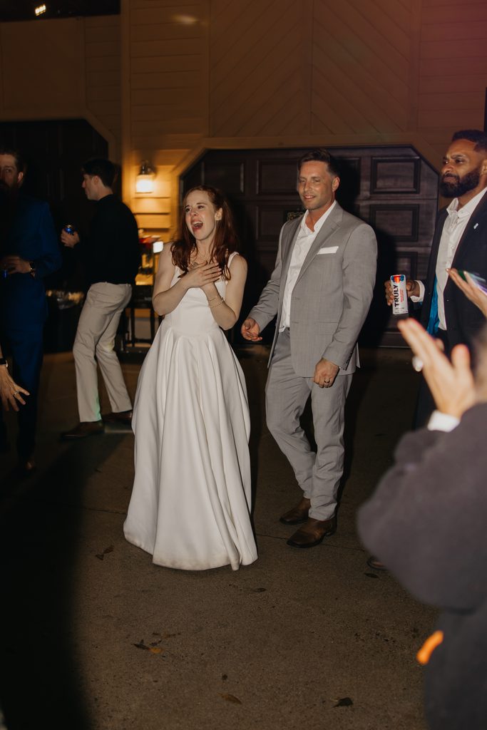 Stephanie laughs with her hand on her chest while Seth smiles beside her on the dance floor